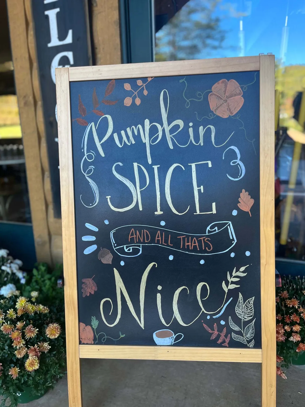 An exterior scene of a cheerful chalkboard sign adorned with seasonal decorations and floral arrangements, suggesting a lively, community-oriented environment perfect for exploration and gathering. The festive ambiance hints at Asheville's vibrant culture and local experiences.