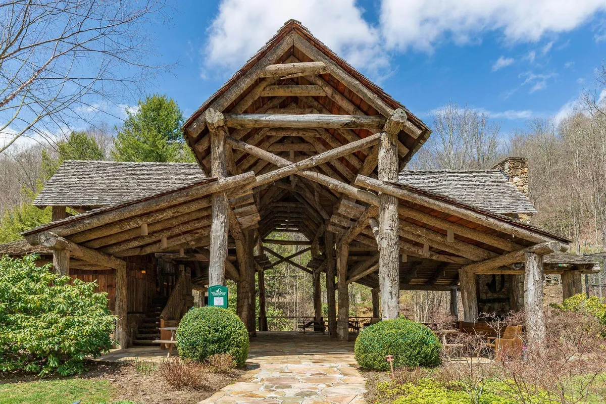 A rustic log cabin exterior with a charming stone pathway and well-tended landscaping, evoking a cozy and welcoming base after a day of exploration. The warm, golden light suggests sunset or evening, inviting guests to gather and unwind.