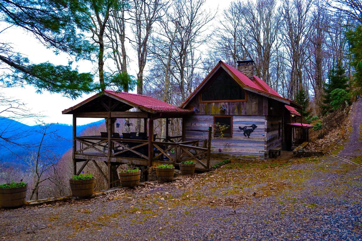 A cozy wooden cabin with a covered porch offering rustic charm and wide-reaching mountain views, perfect for relaxing or stargazing. The outdoor space is inviting and seamlessly blends the home into its natural setting.
